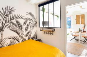 a bedroom with a yellow bed with a palm mural on the wall at « Kraou Kezeg » à 50m de la mer - 2/4 pers. in Saint Malo
