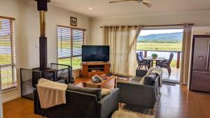 a living room with couches and a flat screen tv at Water View Country Cottage in Yandina Creek