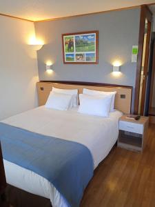 a bedroom with a large bed with white pillows at H&ocirc;tel Restaurant Campanile Aurillac in Aurillac