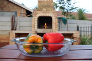 a bowl of peppers on a wooden table with a fireplace at Housemartin Guest House in Klerksdorp