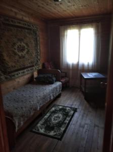 Schlafzimmer mit einem Bett, einem Fenster und einem Teppich in der Unterkunft Семейный домик под ключ у моря в Новом Афоне! in Novy Afon