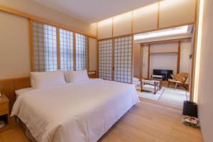 een slaapkamer met een wit bed en een woonkamer bij 金漫會館-金瓜石九份景觀民宿-Jien Mount Villas in Jiufen
