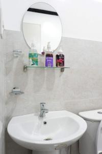 a bathroom with a sink and a mirror and a toilet at LMIRAMARS Tourist Inn in Itaytay