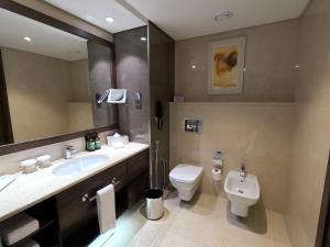 een badkamer met een wastafel, een toilet en een spiegel bij Crowne Plaza Kuwait Al Thuraya City, an IHG Hotel in Koeweit