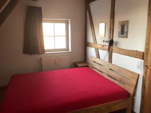 um quarto com uma cama vermelha e uma janela em Ferienwohnung Mainidylle em Winterhausen