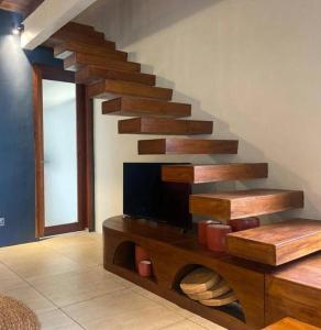 a living room with a wooden staircase with a tv at La Villa Loca in Gili Air