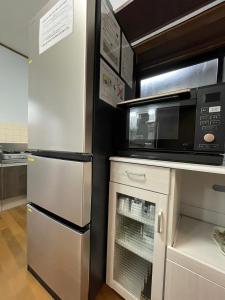 a kitchen with a microwave and a refrigerator at Hana Azusa in Yufuin