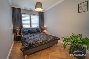 ein Schlafzimmer mit einem Bett und einer Topfpflanze in der Unterkunft Apartament Panorama in Olsztyn