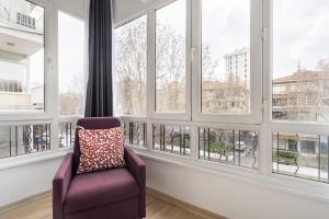 een paarse stoel in een kamer met ramen bij Specious and Stylish Apartment Near Bagdat Street with Excellent Location in Kadikoy in Istanbul