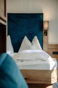 a bed with white pillows and a blue headboard at Lerchs Landhotel in Sankt Johann im Pongau