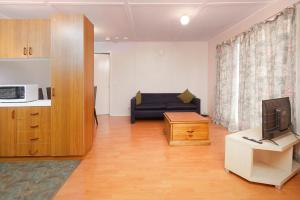 uma sala de estar com um sofá e uma televisão em Melbourne Guest house em Doveton