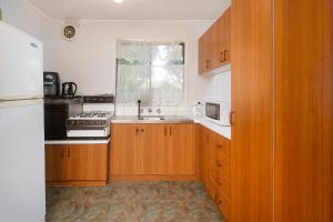 uma cozinha com armários de madeira, um lavatório e uma janela em Melbourne Guest house em Doveton