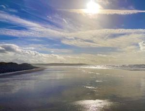a view of a beach with the sun reflecting in the water at Bay View Lodge, Brynowen in Borth