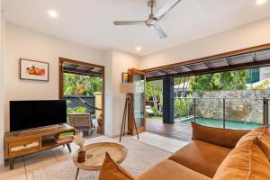 a living room with a couch and a tv at The Savannah Villa in Port Douglas