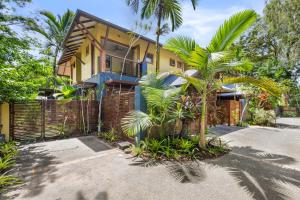 een geel huis met een hek en palmbomen bij The Savannah Villa in Port Douglas