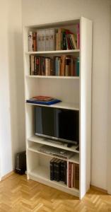 a white book shelf with a tv and books at Traumhafte Wohnung im Herzen von Leipzig in Leipzig