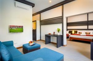 a living room with a blue couch and a bed at Reveal Angkor Hotel in Siem Reap