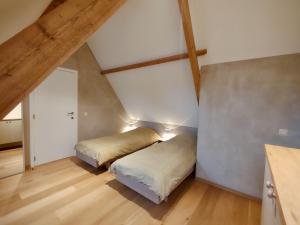 two beds in a attic room with wooden floors at Nachtegael Hoekhuis, knusse woning met prachtig vergezicht in Kluisbergen