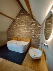een badkamer met een wit bad en een wastafel bij Nachtegael Hoekhuis, knusse woning met prachtig vergezicht in Kluisbergen