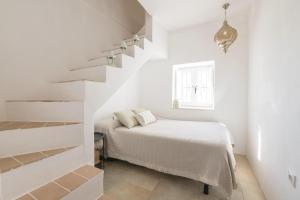 um quarto branco com uma cama e escadas em Casa Manuela em Vejer de la Frontera