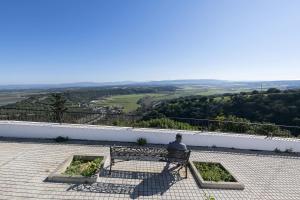 a man sitting on a bench looking out at the valley at Casa Manuela in Vejer de la Frontera