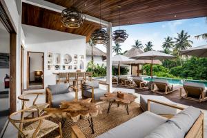 una sala de estar al aire libre con mesas y sillas y una piscina en Villa Tchikobo by BaliSuperHost, en Ubud
