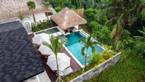 einen Blick über einen Pool mit Stühlen und einem Sonnenschirm in der Unterkunft Villa Tchikobo by BaliSuperHost in Ubud