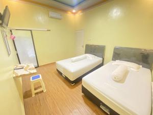 um pequeno quarto com duas camas e uma balança em Homestay RN near Taman Bambu Runcing Polewali Mitra RedDoorz em Matakali
