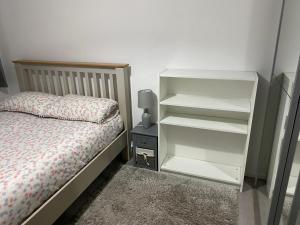 ein Schlafzimmer mit einem Bett und einem weißen Bücherregal in der Unterkunft Modern 2 bedrooms fully equipped Apartment with garden, Free Parking, Free Wifi in Dagenham