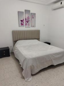 ein Schlafzimmer mit einem Bett mit vier Bildern an der Wand in der Unterkunft Yasmine appartement A7 in Nabeul