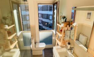 a bathroom with a toilet and a sink and a window at Casa Carlini Homestay in Getxo
