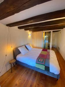 a bedroom with a large bed with a wooden floor at Chambre sur terrasse in Nendaz