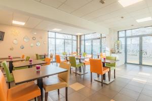 a restaurant with tables and chairs and windows at Appart'City Classic Caen in Caen