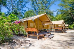 gelbes Zelt mit Stühlen und Bäumen im Hintergrund in der Unterkunft Ara Dinawan Island Resort in Papar