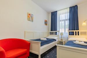 チェスケー・ブジェヨヴィツェにあるHotel Amadeusのベッドルーム1室(ベッド2台、赤い椅子付)