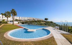 - une piscine en face d'un bâtiment donnant sur l'océan dans l'établissement Adosado con vistas exclusivas - Montesol ALBERT VILLAS, à Alcossebre