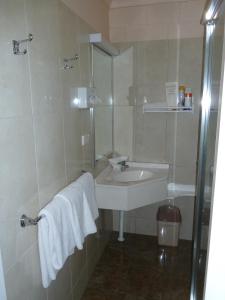 uma casa de banho com um lavatório e um chuveiro com um espelho. em Mandalay Motel em Roma