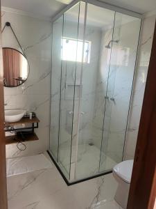uma casa de banho com uma cabina de duche em vidro e um WC. em Pousada e Restaurante Casa Cida e Evandro em Gaspar