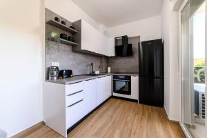 a kitchen with white cabinets and a black refrigerator at Apartman Ivana in Šibenik