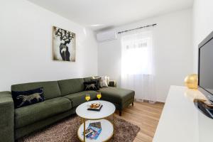 sala de estar con sofá verde y TV en Apartman Ivana, en Šibenik