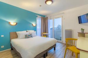 - une chambre avec un grand lit et un mur bleu dans l'établissement Appart'City Classic Caen, à Caen