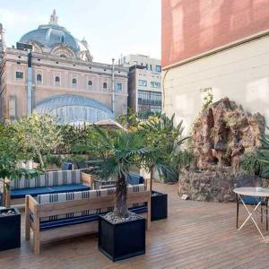 un patio avec bancs et arbres en pot et un bâtiment dans l'établissement Praktik Rambla, à Barcelone