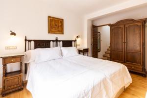 1 dormitorio con 1 cama blanca grande y armario de madera en La Casita de Elvira, en Nigüelas