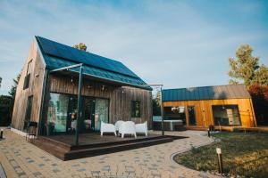 een huis met twee witte stoelen op een patio bij Brīvdienu māja Saule in Mērsrags