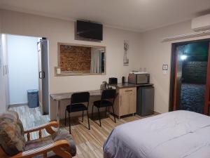 um quarto com uma cama e uma cozinha com uma mesa em Twins Guest House Astoni em Vanderbijlpark