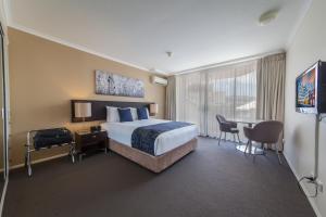 a bedroom with a bed, chair, desk and a television at West End Central Apartments in Brisbane