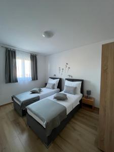 two beds in a room with white walls and wood floors at Apartments Magdalena in Stobreč