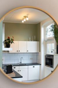 a kitchen with white cabinets and a mirror at Sfeervol verblijf in oude gemeentehuis Eenrum. in Eenrum