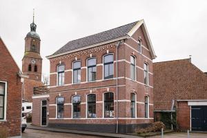 a large brick building with a clock tower at Sfeervol verblijf in oude gemeentehuis Eenrum. in Eenrum