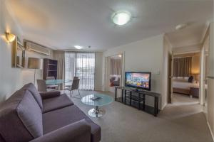uma sala de estar com um sofá, uma televisão e uma mesa em West End Central Apartments em Brisbane